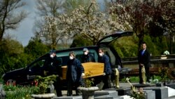 Undertakers wearing protection masks to protect from the coronavirus, carry a coffin to a burial at Salvador cemetery during the coronavirus outbreak, near to Vitoria, northern Spain, Monday, March 30, 2020.