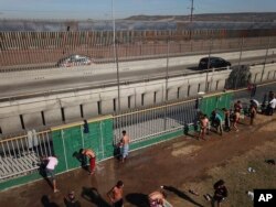Central American migrants bathe at a temporary shelter, near barriers that separate Mexico and the United States, at a temporary shelter in Tijuana, Mexico, Nov. 17, 2018.