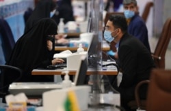 Seorang pria memberikan informasi identitasnya kepada petugas pendaftaran calon presiden di Kementerian Dalam Negeri Iran di Teheran, Selasa, 11 Mei 2021.