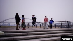 Warga menggunakan masker pelindung mulut bermain di sebuah taman di Shanghai di tengah merebaknya wabah virus corona di China, Jumat, 6 Maret 2020. (Foto: Reuters) 