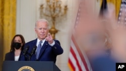 美国总统拜登在白宫就获得两党支持的基础设施法案发表讲话后，在回答媒体提问时做手势。副总统哈里斯在一旁聆听。（2021年8月10日）