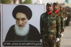 FILE - Members of the Liwa al-Tafuf 13th Brigade of Iraq's Shi'ite Muslim Hashed al-Shaabi paramilitary carry a placard showing Iraqi Ayatollah Ali Sistani during a graduation ceremony at a training center in Karbala, Iraq, Aug. 30, 2019.