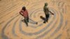 FILE - Workers spread maize crop for drying at a wholesale grain market in the northern Indian city of Chandigarh, June 12, 2012. 