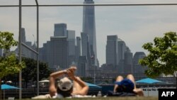 Wadansu mutane kwance kan ziyawa a bakin rafi sabili da zafi a birnin New York