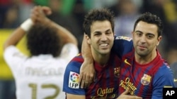 FC Barcelona's Cesc Fabregas, center, celebrates with Xavi Hernandez, right, during the Spanish La Liga soccer match against Real Madrid at the Santiago Bernabeu stadium in Madrid, Spain.