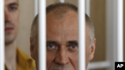 A former opposition presidential candidate Nikolai Statkevich sits in a cage during a court session in Minsk, Belarus, Thursday, May 26, 2011