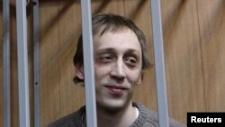 Dancer Pavel Dmitrichenko looks out from the defendant's holding cell during a hearing in Moscow on October 22, 2013. Dmitrichenko, who made his name on stage at Moscow's Bolshoi Theatre, went on trial on Tuesday for an acid attack that nearly blinded the ballet's artistic director. 
