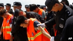 រូបឯកសារ៖ ជនជាតិចិនក្នុង​ឯកសណ្ឋានអាវពណ៌ទឹកក្រូច ត្រូវបានចាប់ខ្លួន​ និង​បញ្ជូន​ទៅ​ប្រទេសចិនវិញ ដោយ​មន្ត្រីប៉ូលិសចិន មុនពេលពួកគេឡើងយន្តហោះចេញពីអាកាសយានដ្ឋានអន្តរជាតិភ្នំពេញនៃប្រទេសកម្ពុជា កាលពីថ្ងៃទី១២ ខែតុលា ឆ្នាំ២០១៧។