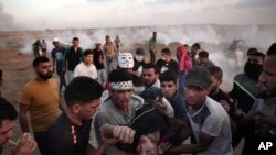 Palestinian protesters carry an injured man during a protest at the Gaza Strip's border with Israel, Friday, May 11, 2018. Gaza activists burned tires near the sealed border with Israel on Friday in a seventh weekly protest aimed at shaking off a decade-old blockade of their territory.