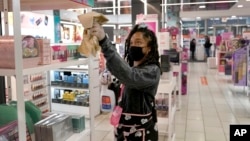 FILE - Tamia Prescott sanitizes a cosmetic display Thursday, Nov. 19, 2020, at a beauty store in Chicago. (AP Photo/Charles Rex Arbogast)