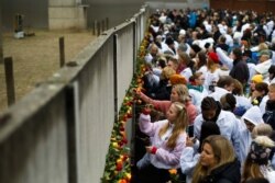 FILE - People stuck flowers in remains of the Berlin Wall during a commemoration ceremony to celebrate the 30th anniversary of the fall of the Berlin Wall at Bernauer Strasse in Berlin, Nov. 9, 2019.