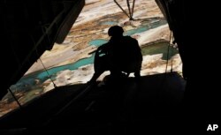 FILE - A U.S. Marine helicopter door gunner holds a heavy machine gun during a flight over Nimroz province on the border with the volatile Helmand province in southern Afghanistan.