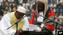In this photo taken Feb. 18, 2017, Gambia President Adama Barrow, left, signs a document during his inauguration ceremony in Banjul, Gambia. 