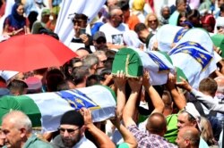 FILE - Bosnian Muslims carry caskets of the 33 newly identified bodies of the 1995 Srebrenica massacre before their inhumation at the Potocari Memorial Cemetery near the Eastern-Bosnian town of Srebrenica.