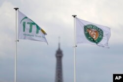 FILE - he Eiffel Tower is framed by the ITF flag and the Roland Garros stadium flag during the French Open tennis tournament at the Roland Garros stadium, Monday, May 29, 2017 in Paris. (AP Photo/Petr David Josek)