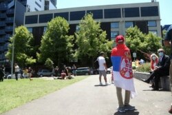 FILE - A fan of Serbia's Novak Djokovic stands outside the Park Hotel, used as an immigration detention hotel where the world's No. 1-ranked tennis player was detained in Melbourne, Jan. 9, 2022.
