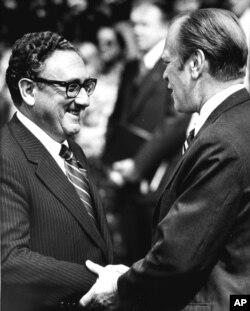 រូបឯកសារ៖ លោក​ប្រធានាធិបតី Gerald Ford និង​លោក​រដ្ឋមន្ត្រី​ការបរទេស Henry Kissinger ចាប់​ដៃ​នៅ​សេតវិមាន​កាលពី​ថ្ងៃ​ទី១៥ ខែ​ឧសភា ឆ្នាំ១៩៧៥។ មុន​នេះ​លោក​ប្រធានាធិបតី​បាន​ប្រកាស​ថា កង​ម៉ារីន​របស់​អាមេរិក​បាន​រកឃើញ​កប៉ាល Mayaguez និង​មនុស្ស​៤០នាក់​នៅ​ក្បែរ​កោះតាង។ (រូបថត AP)