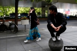 FILE - A Uighur man looks at a passing Han woman outside of his restaurant in Shanghai, April 23, 2014.