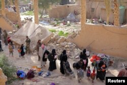 Islamic state fighters and their families walk as they surrendered in the village of Baghuz, Deir Al Zor province, Syria, March 12.