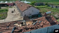 In this photo released by China's Xinhua News Agency, a man stands near damaged buildings and farm fields after a devastating storm in Nantong in eastern China's Jiangsu Province, May 1, 2021. 