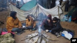 Migrants from the Middle East and elsewhere warm up at a fire near the Belarus-Poland border near Grodno, Belarus, Nov. 11, 2021.