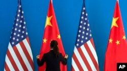 A Chinese woman adjusts the Chinese national flag near U.S. national flags, file photo. 