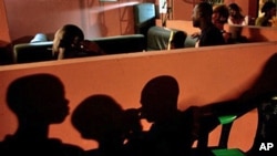 Residents watch TV in Abidjan, 03 Nov 2010, as election results set the stage for a runoff election