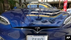 In this Oct. 24, 2016, file photo, palm trees are reflected on the hood of a Tesla Model S on display in downtown Los Angeles. (AP Photo/Richard Vogel, File)
