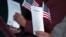 FILE - Participants hold the "Oath of Allegiance" and American flags during a naturalization ceremony at the National Archives in Washington, Dec. 15, 2015.