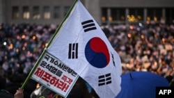 A protester holds the South Korea flag during a candlelight rally calling for the ouster of South Korea President Yoon Suk Yeol at the National Assembly in Seoul on December 5, 2024.