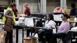 Seorang pengamat pemilu (kiri) memperhatikan saat petugas pemungutan suara di Fulton County memindai surat suara untuk penghitungan ulang, 25 November 2020.