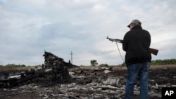 Pemberontak pro-Rusia menjaga lokasi jatuhnya pesawat Malaysia Airlines dekat desa Hrabove, Ukraina timur (19/7). (AP/Evgeniy Maloletka)