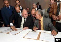 FILE - Awad Mohammed Abdul-Sadiq (L), the first deputy head of the Tripoli-based General National Congress (GNC), and Ibrahim Fethi Amish from the internationally recognised House of Representatives sign documents after reaching an agreement.