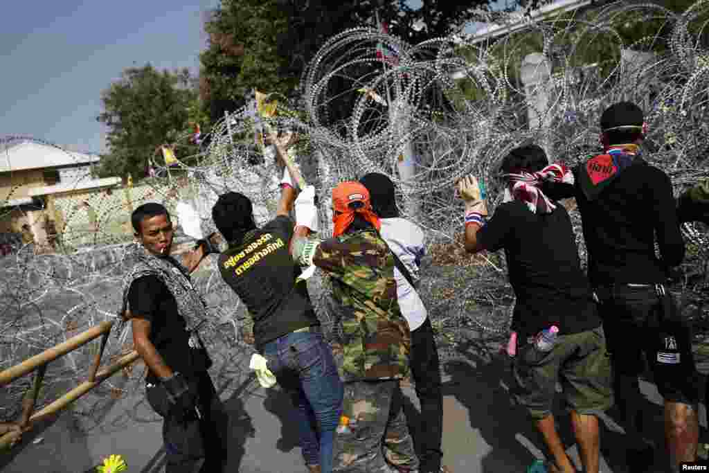 Anti-government protesters remove barbed wire after briefly entering the compound of the prime minister&#39;s office, known as Government House, in Bangkok, Dec. 12, 2013. 