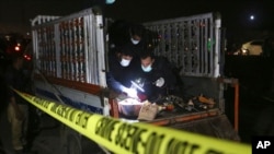 Investigators examine a truck at the site of an explosives attack, in Karachi, Pakistan, Aug. 14, 2021. 