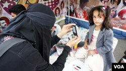 Nadia Abudllah mengambil foto seorang gadis cilik di tengah-tengah berlangsungnya protes anti-pemerintah di Sana'a (20/2).