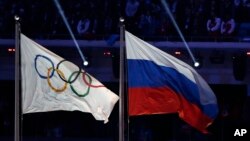 FILE - The Russian national flag (R) flies next to the Olympic flag during the closing ceremony of the 2014 Winter Olympics in Sochi, Russia, Feb. 23, 2014. 
