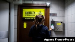 រូបឯកសារ៖ ស្ត្រី​ម្នាក់ ឈរ​នៅ​ក្បែរ​ទ្វារ​​ចូល​ការិយាល័យ​របស់​អង្គការ​លើកលែង​ទោស​អន្តរជាតិ Amnesty International នៅ​ទីក្រុង​ហុងកុង។