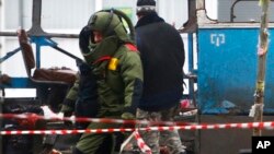 A demolition expert clad in a protective gear walks along the wreckage of a trolleybus in Volgograd, Russia, Dec. 30, 2013.