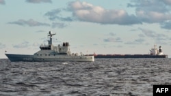 中国船舶“伊鹏3号”散货船(右)停泊在丹麦日德兰半岛附近的卡特加特海。丹麦海军巡逻艇（左前）正在进行监视。（2024年11月20日）