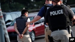 A man is taken into custody at a Koch Foods Inc. plant in Morton, Miss., Aug. 7, 2019.