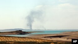 Asap tampak mengepul dalam pertempuran memperebutkan bendungan di luar kota Mosul, Irak (18/8).