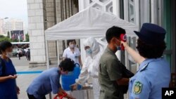 13일 평양 기차역 입구에서 승객들이 코로나바이러스 감염 예방을 위해 손소독제로 손을 소독한 뒤 체온을 측정받고 있다.