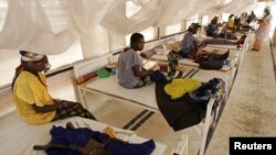 FILE - Women and their babies suffering from malnutrition sit on beds at a make shift hospital in Maradi, Niger, July 30, 2005. 