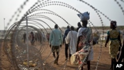 FILE - A file photo taken Jan. 19, 2016 shows displaced people walking next to a razor wire fence at the United Nations base in the capital Juba, South Sudan. 