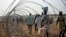 FILE - Displaced people walking next to a razor wire fence at the United Nations base in the capital Juba, South Sudan. 