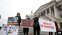 Protesters hold signs and sing outside the U.S. Capitol, Jan 31, 2020, in Washington, as Senators continue the impeachment trial for President Donald Trump.