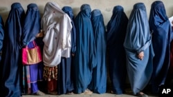 FILE - Women wait to receive food rations in Kabul, Afghanistan, May 23, 2023. The United Nations Security Council adopted a resolution on Friday calling for the appointment of a special envoy for Afghanistan to increase engagement with the country and its Taliban leaders.