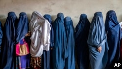 FILE - Afghan women wait to receive food rations distributed by a humanitarian aid group in Kabul, Afghanistan, on May 23, 2023.