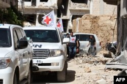 Vehicles of the International Committee of the Red Cross (ICRC) and the United Nations wait on a street after an aid convoy entered the rebel-held Syrian town of Daraya, southwest of the capital Damascus, on June 1, 2016.